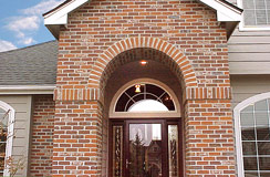 Massive brick archway entry features Pella Cherry wood storm door, leaded glass entry door and 2 side-light leaded glass windows...